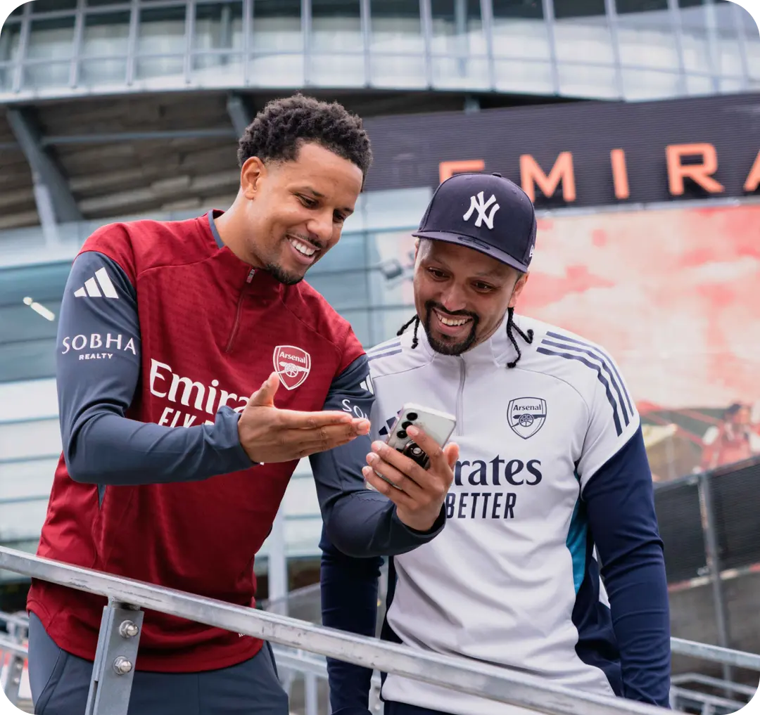 Two fans looking at a phone outside the ground